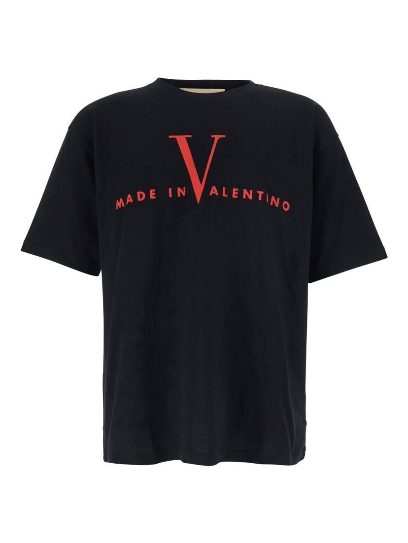 تيشيرت أسود برقبة دائرية وشعار مطبوع على الجهة الأمامية وأكتاف منسدلة، مصنوع من القطن الرجالي